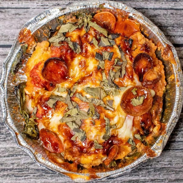 Totally Baked Pizza's baked pizza with pepperoni, cheese, and basil in a foil pan.